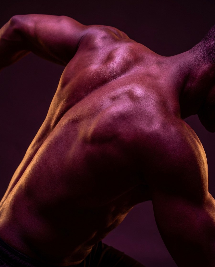Athletic shoulder and back lit in magenta and amber
